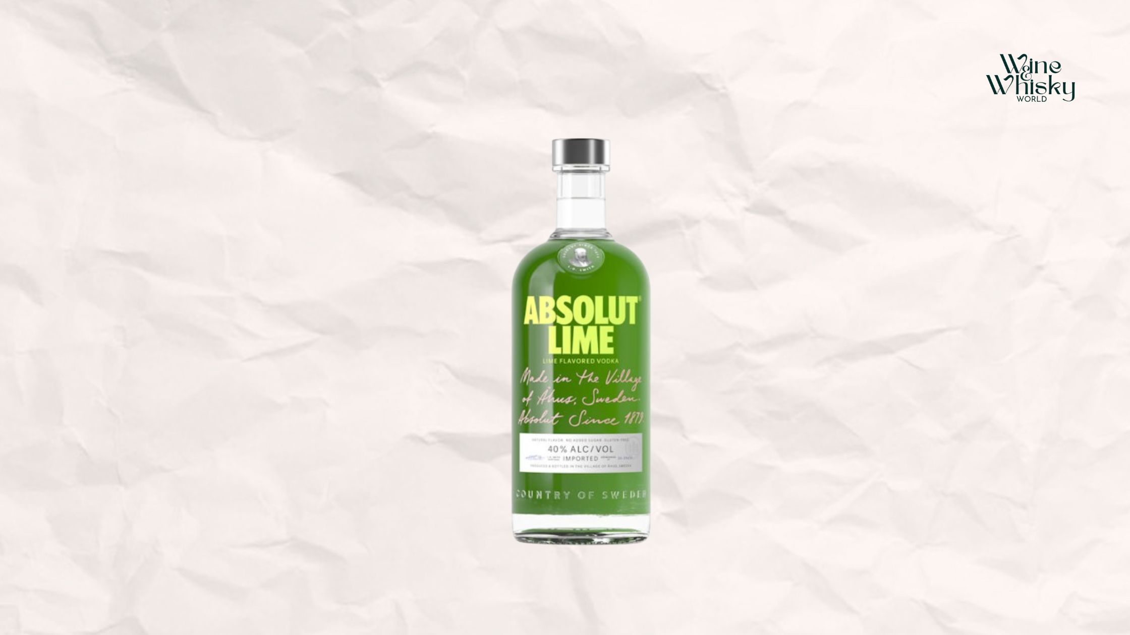 Clear glass bottle of Absolut Vodka with lime and black text on the label, reading 'Absolut Vodka', displayed against a crumpled white paper background with the Wine Whisky World logo in the top right corner.